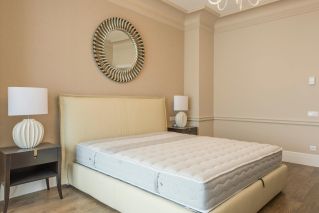 Spacious bedroom featuring modern decor, elegant lighting, and a plush bed with neutral tones.